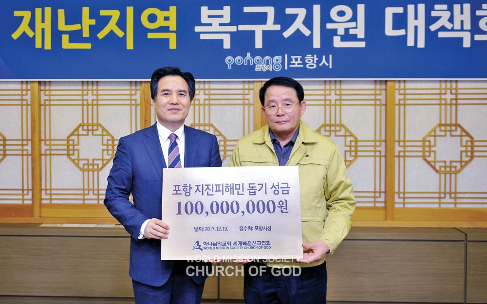 2017년 12월 19일, 하나님의 교회 총회장 김주철 목사(왼쪽)가 포항시 최웅 부시장에게 지진피해민 돕기 성금 1억 원을 전달했다.